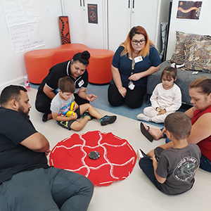 A group of adults and children sit in a circle.