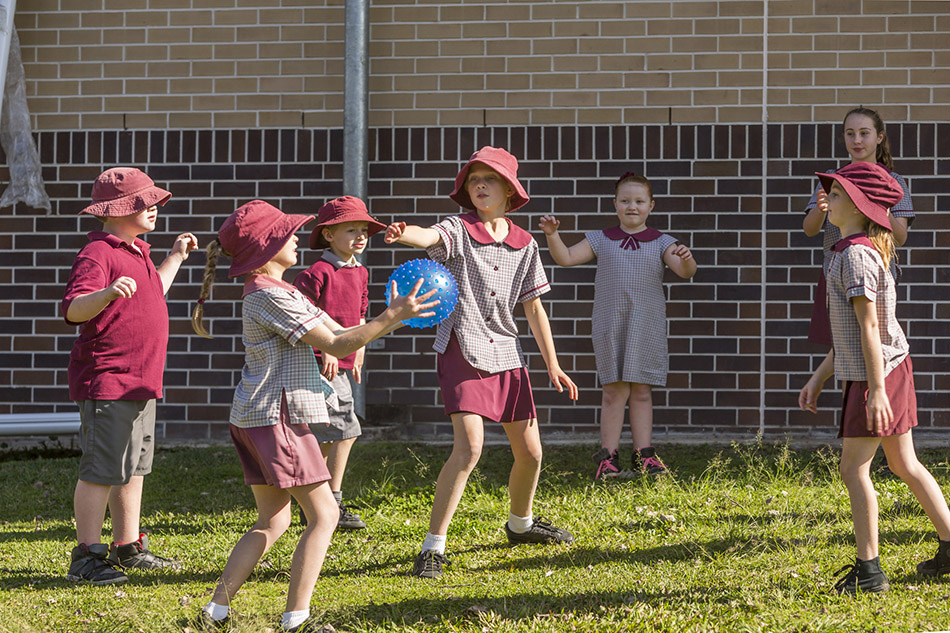 seven children in school uniforms playing a ball game outside